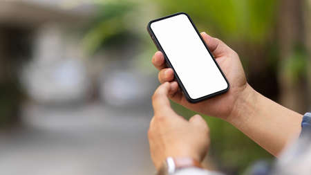 Close up view of male hands using smartphone include clipping path screen in blurred outdoor backgroundの写真素材