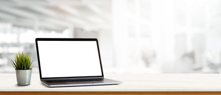 Simple workspace with laptop and plant pot on white desk in blurred background, clipping pathの写真素材