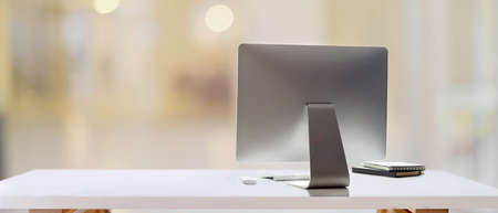 Cropped shot of white table with computer device and copy space in blurred backgroundの写真素材
