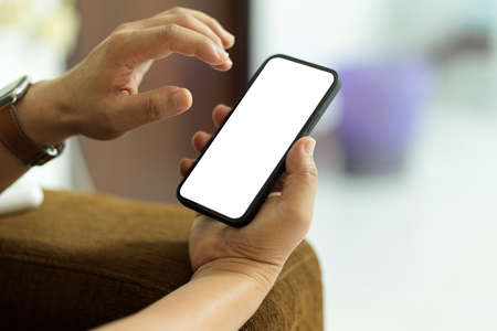 Close up view of male hand using smartphone with mock-up screen in blurred background, clipping pathの写真素材