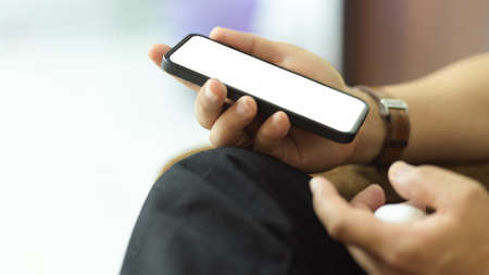 Side view of male hand holding smartphone include clipping path screen while relaxed sitting on sofa
