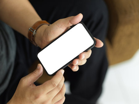 Top view of male hands holding smartphone and showing mock-up screen to camera, clipping pathの写真素材