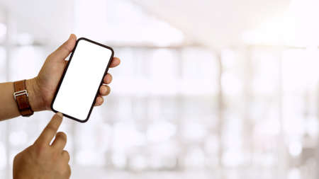 Close up view of hands using smartphone and showing mock-up screen to camera in blurred background, clipping pathの写真素材