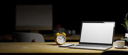 3D rendering, laptop with mock-up screen on wooden table with smartphone, cup and clock at night, 3D illustrationの写真素材