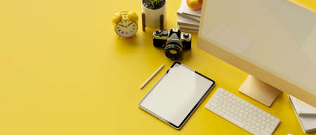 3D rendering, computer monitor, digital tablet with mock-up screen, camera and stationery on yellow background, 3D illustrationの写真素材