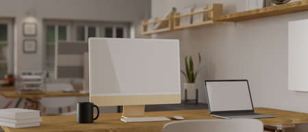 3D rendering, computer and laptop with mock-up screen and office supplies on wooden table in cozy office room, 3D illustrationの写真素材