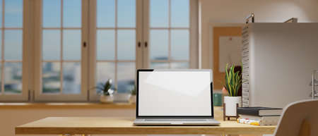 3D rendering, laptop with mock-up screen on wooden table beside the window in cozy home office room, 3D illustrationの写真素材