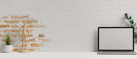 Laptop with mock-up screen on white table with decorations and brick wall background, 3D rendering, 3D illustrationの写真素材