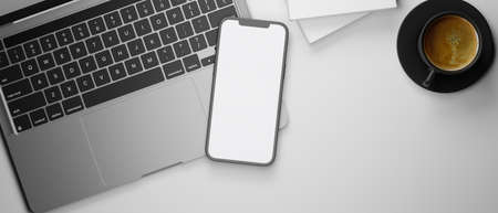 Smartphone with mock-up screen on laptop keyboard, coffee cup and books on white desk, 3D rendering, 3D illustrationの写真素材