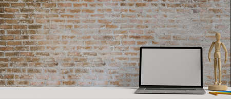 Mock-up computer laptop screen on white table with wooden figure, copy space and brick wall, 3D rendering, 3D illustrationの写真素材