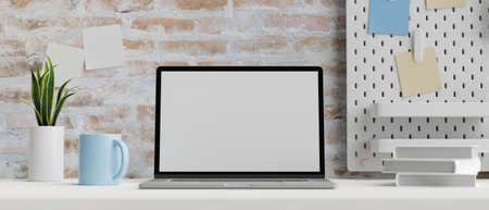 Computer laptop with mock-up screen on white table with books, mug and plant pot, 3D rendering, 3D illustrationの写真素材
