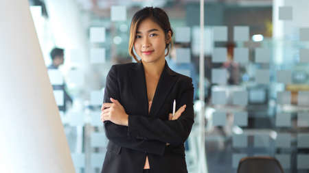Half-length portrait of young businesswoman in black suit smiling to cameraの写真素材