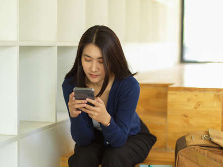 Close up view female teenager using smartphone while relaxed sitting in universityの写真素材
