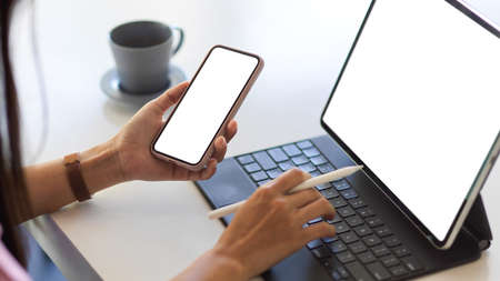 Close up view of female hand working with digital tablet and smartphone with mock-up screenの写真素材