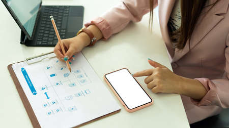 Top view of businesswoman working with paperwork and smartphone with mock-up screenの写真素材