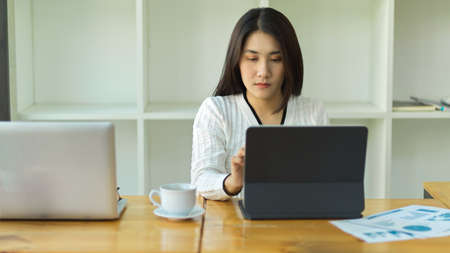 Portrait of female worker using digital tablet on wooden table in working spaceの写真素材