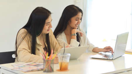 Side view of two female students consulting on their group assignment while studying in classroomの写真素材