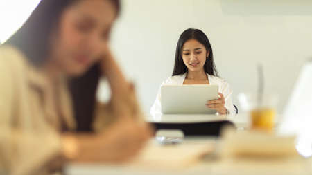Female student using digital tablet while sitting in the back âside in classroomの写真素材