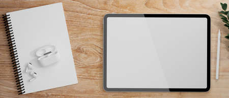 Digital tablet with mock-up screen, earphones and notebook on wooden table, 3D rendering, 3D illustrationの写真素材