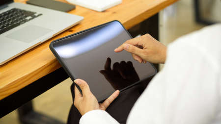Side view of businesswoman hand using digital tablet while sitting at workspace