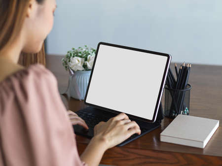 Close up view of female working with digital tablet with mock-up screen on wooden tableの写真素材