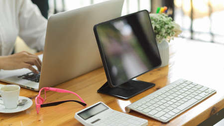 Side view of simple workspace with tablet monitor, keyboard and calculator on meeting tableの写真素材