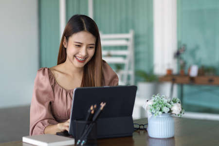 Portrait of smiling female working with digital tablet and stationery in relaxing corner at officeの写真素材