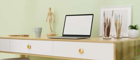 Computer laptop with mock-up screen on the desk with paint tools and decorations, 3D rendering, 3D illustrationの写真素材