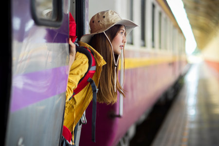 Side view of young female backpacker stepping down the train, traveling conceptの写真素材