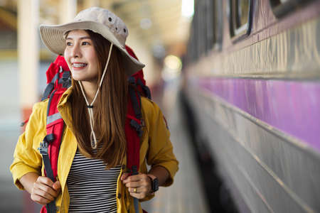 Happy female traveller smiling while walking to get on the train to travel, travelling conceptの写真素材