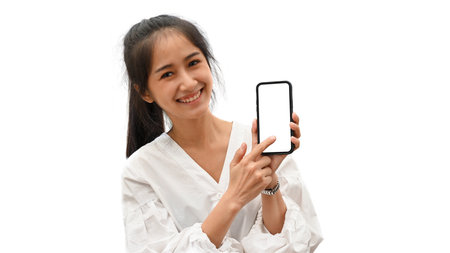 Pretty female smiling and showing smartphone with mock-up screen isolated in white backgroundの写真素材