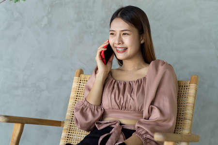 Portrait of young beautiful female smiling while talking on the phone in relaxing cornerの写真素材