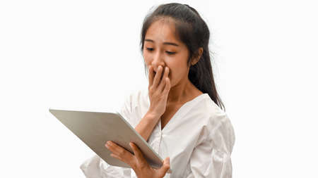 Young female feeling amaze while looking on digital tablet isolated in white backgroundの写真素材