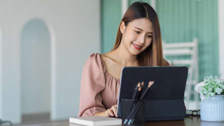 Portrait of female office worker working with digital tablet and stationery on portable workspaceの写真素材