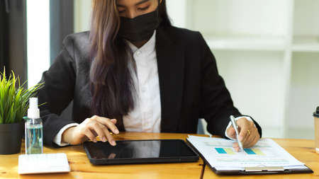 Cropped shot of businesswoman analysing business document with paperwork and digital tabletの写真素材