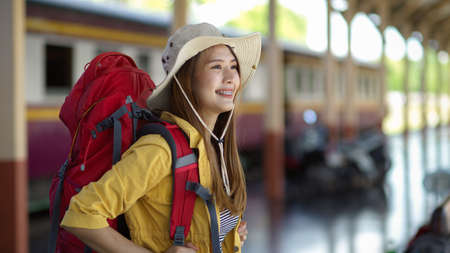 Side view of friendly young female backpacker smiling when arriving at terminalの写真素材