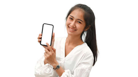 Pretty female smiling and presenting smartphone with mock-up screen isolated in white backgroundの写真素材