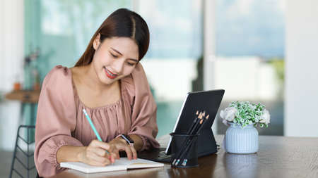 Portrait of female office worker planning her schedule on notebook on portable workspaceの写真素材