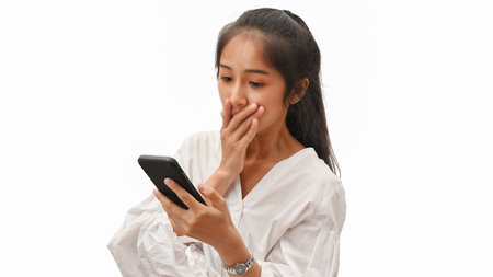 Portrait of female feeling surprise while using smartphone isolated in white backgroundの写真素材