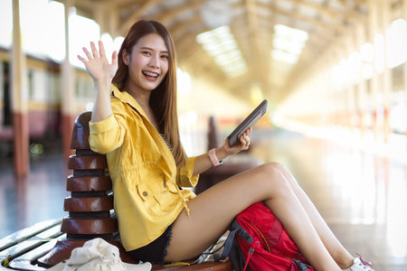 Smiling female traveller say hi and showing five palm leaves hand to camera while sitting at terminalの写真素材