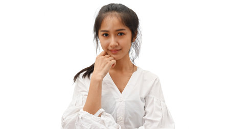 Half-length portrait of young female in white shirt smiling and posting to camera isolated in white backgroundの写真素材