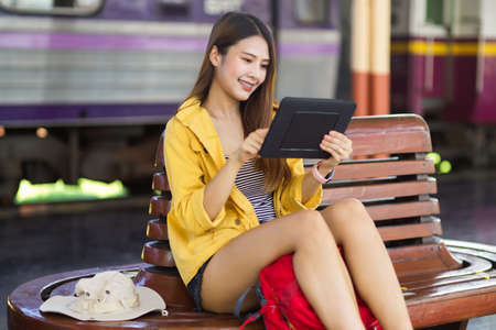 Young female backpacker using digital tablet to check her plan at train stationの写真素材
