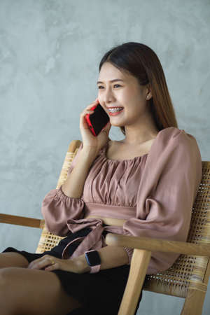 Portrait of female office worker talking on the phone while relaxed sitting in cafeの写真素材
