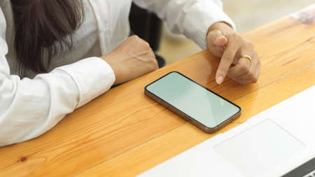 Top view of female hands using smartphone, touching on phone screen on workspaceの写真素材