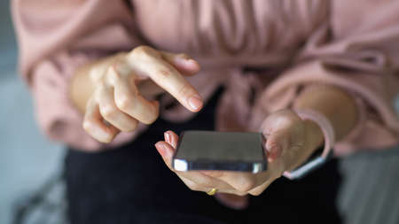 Close up view of female hand using smartphone, finger texting on phone screenの写真素材