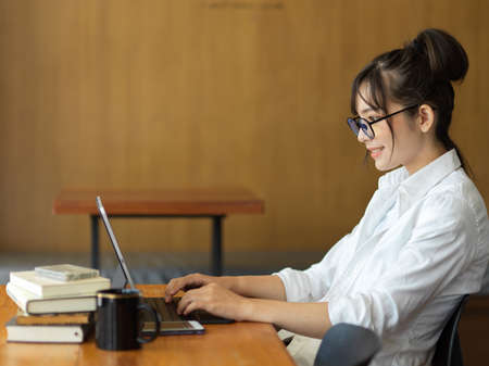 Side view of young female student preparing for upcoming exam with digital tablet and booksの写真素材