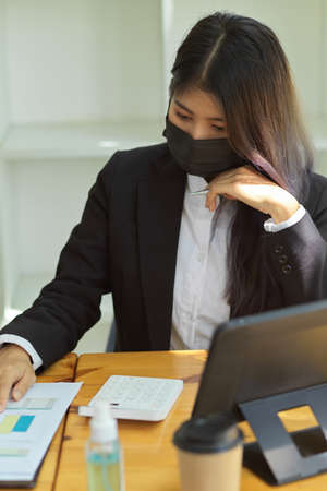 Cropped shot of businesspeople with face mask working with digital tablet and paperwork in officeの写真素材