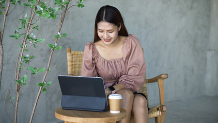 Portrait of happy female office worker using digital tablet while relaxing in cafeの写真素材