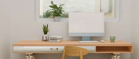 Computer device with mock-up screen on wooden desk with books and plant pot in minimal home office, 3D rendering, 3D illustrationの写真素材