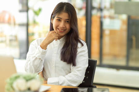 Portrait of female office worker smiling to camera while siting in office roomの写真素材